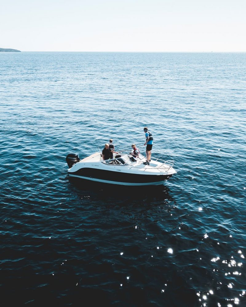 three person on white motorboat at daytime