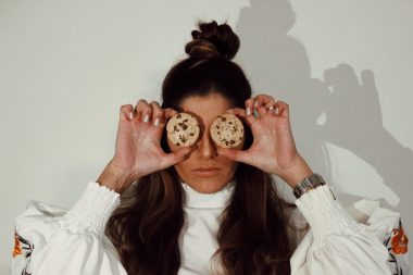 woman covering eyes with two chocolate chip cookies