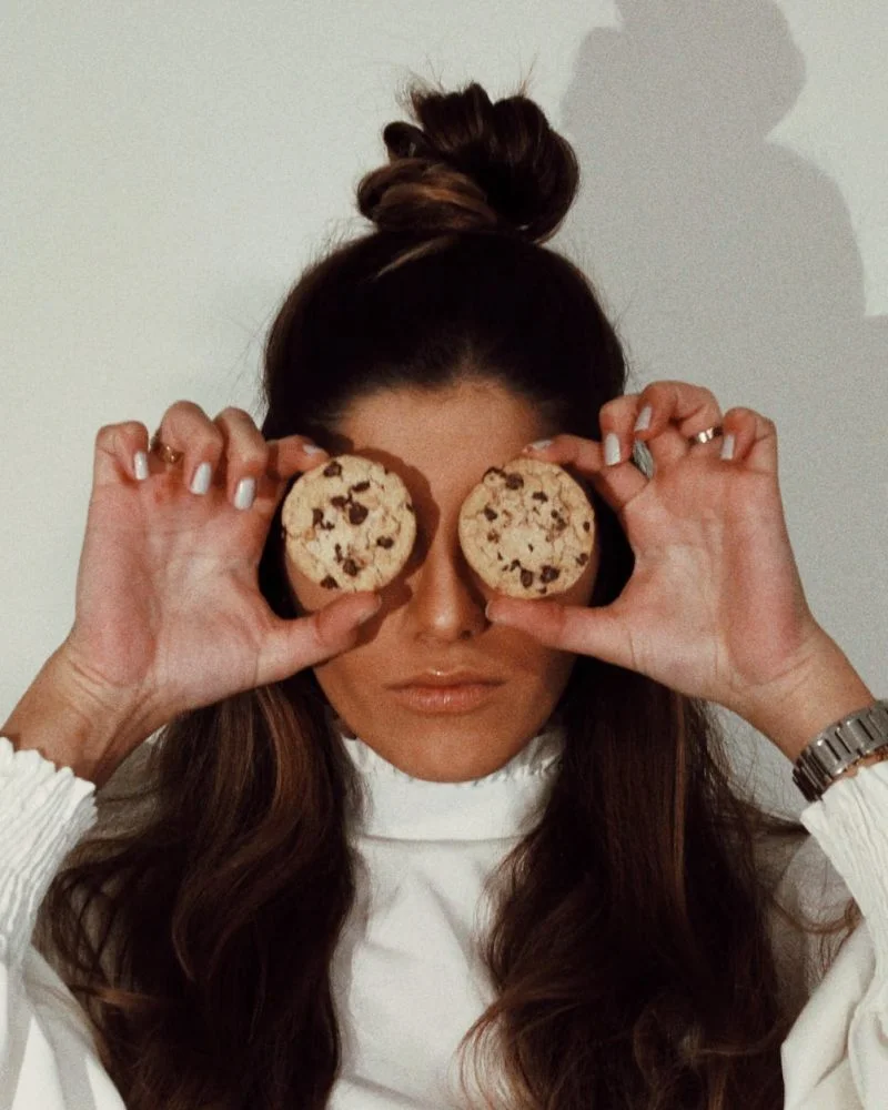 woman covering eyes with two chocolate chip cookies