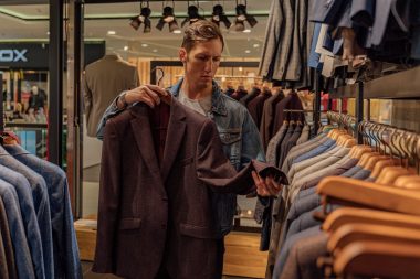 a man looking at a suit jacket in a clothing store